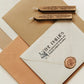 A personalized self inking return address stamp, customized with your shop name and address, stamped on the white envelope, beside it, sealing wax is creating a wax seal on the mail.