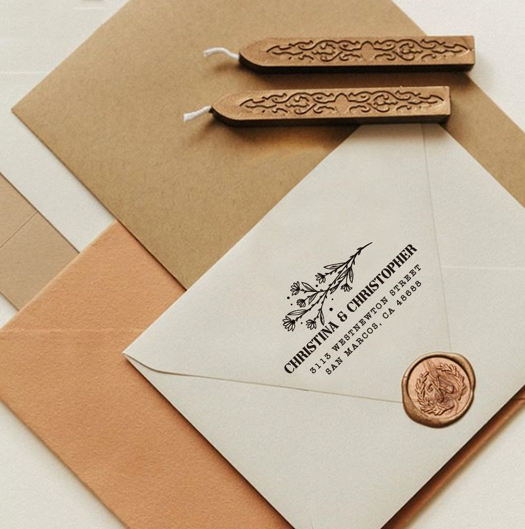 A personalized self inking return address stamp, customized with your name, address and flower, stamped on the white envelope, beside it, sealing wax is creating a wax seal on the mail.