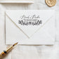 A personalized self inking wedding address stamp, customized with your name, address and flower, stamped on the white envelope, beside it, a wax seal is waiting for sealing the mail.