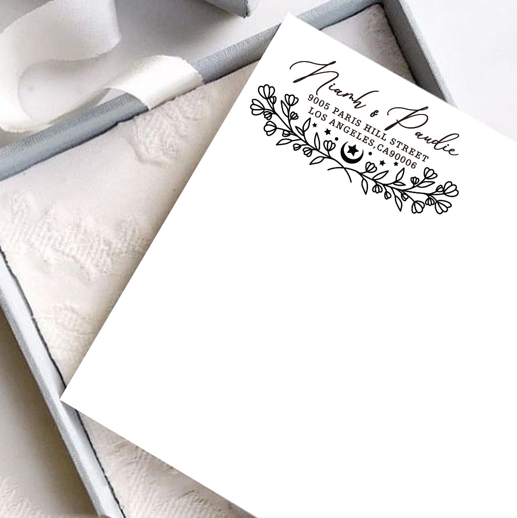 A personalized self inking address stamp, customized with your name, address and flower, stamped on the white card, a gift box is under it.